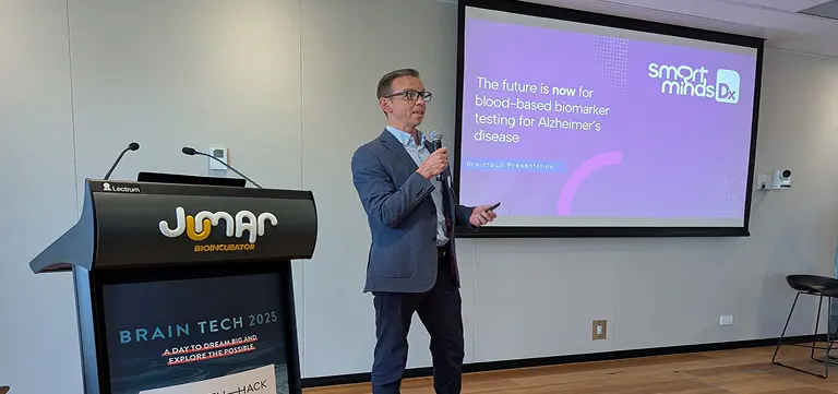Man presenting beside a Smart Minds Dx slide about blood test diagnostics for alzheimers and dementia.