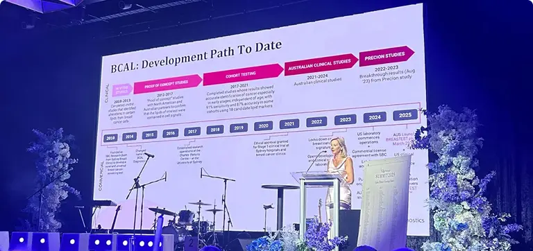 Woman presenting a Smart Minds Dx BCAL slide on dementia diagnostics and blood tests